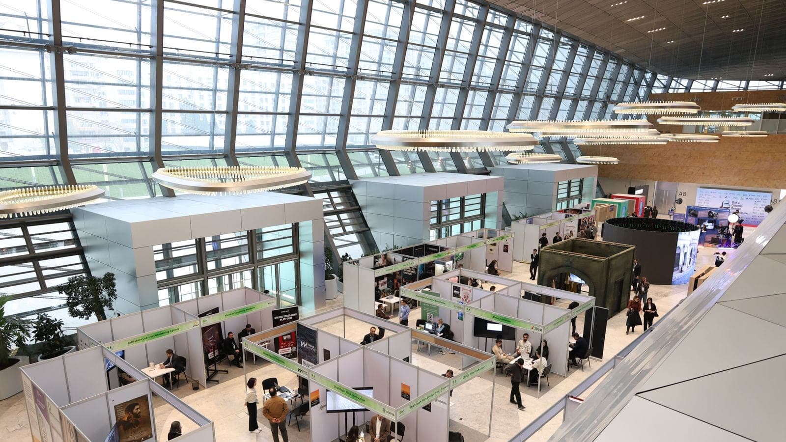 Elevated view of a busy trade show exhibition floor lined with booths