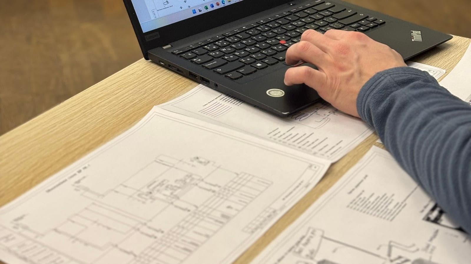 Reviewing printed booth design drawings beside a laptop