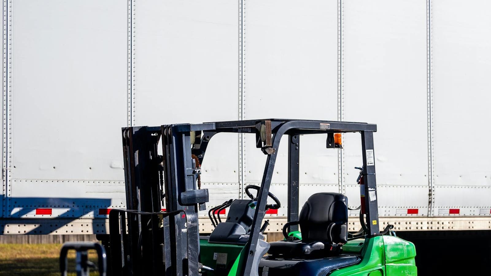 Forklift loading freight beside a shipping trailer